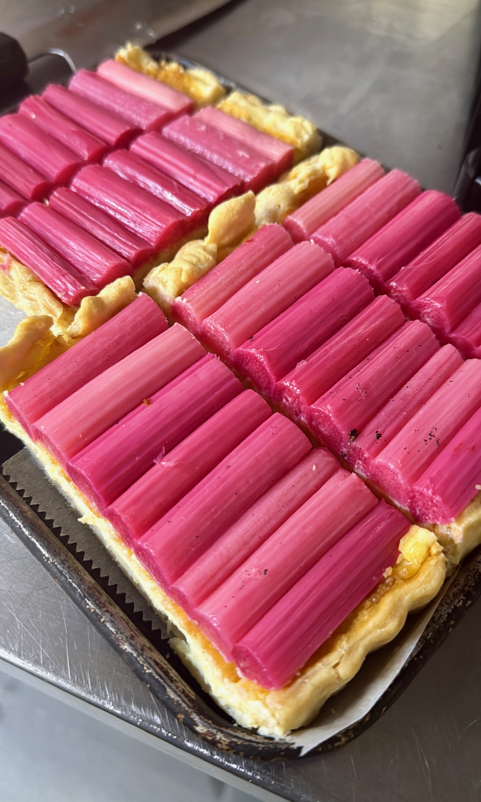 A rhubarb and almond tart, the rhubarb in pink batons across golden custard.
